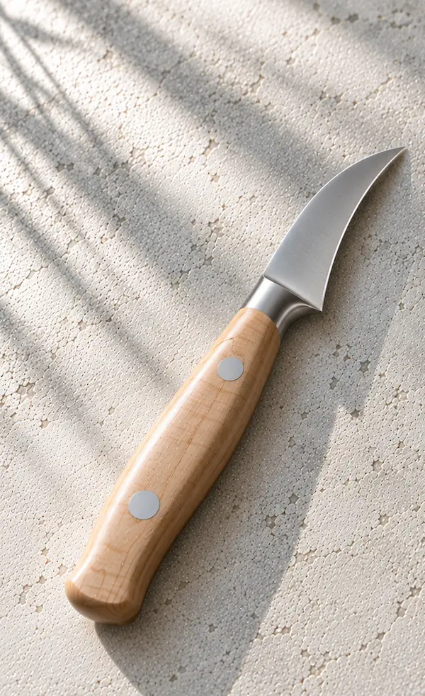 Curved bird’s beak paring knife with a maple handle on chalk-coloured plaster